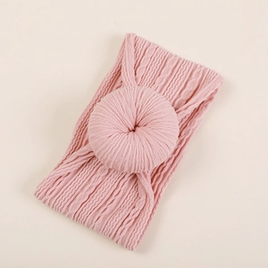 Détail d'un bandeau pour bébé rose doux en tricot avec un grand nœud en forme de donut
