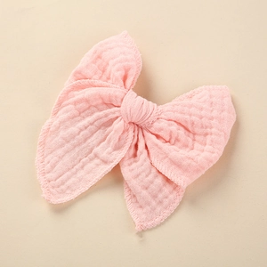 Close-up of pink cotton crepe bow hair clip with soft texture and frayed edges