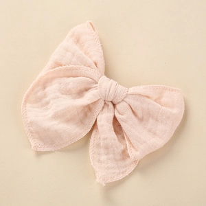 Close-up of large pale pink muslin cotton bow hair clip with natural crinkled texture