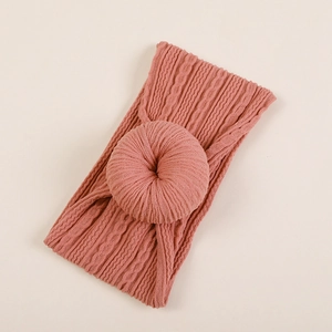 Détail d'un bandeau bébé en maille côtelée vieux rose avec un nœud donut élégant