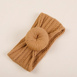 Gros plan d'un bandeau bébé en tricot jacquard marron avec nœud donut et texture côtelée