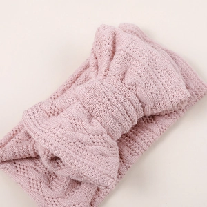Bandeau bébé rose tricoté avec un grand nœud et un motif ajouré délicat
