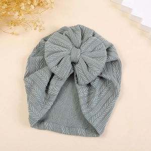 Detail of baby turban hat with herringbone texture and large bow in dusty blue color