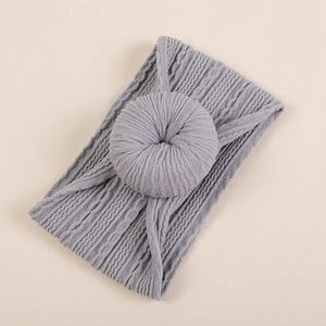 Détail macro du bandeau gris pour bébé avec maille torsadée jacquard et motif de nœud donut