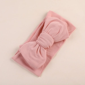 Detail view of pink baby headband made of soft milk silk fabric with a large bow