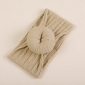 Gros plan d'un bandeau bébé en tricot beige avec motif torsadé et nœud donut