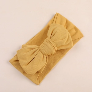 Detail of soft ginger yellow oversized bow headband with elastic knit fabric texture