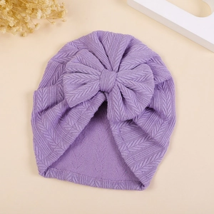 Detail of purple knitted baby turban hat with wheat ear bow and delicate V-stitch texture