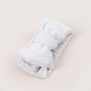 Gros plan détaillé du bandeau blanc en tricot pour bébé avec un grand nœud jacquard