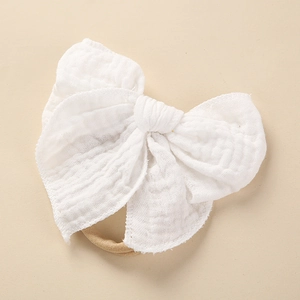 Detail einer weichen, weißen Mull-Schleife und eines hochelastischen Baby-Stirnbands