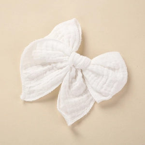 Close-up of white cotton muslin bow hair clip featuring soft textured fabric and stitched edges