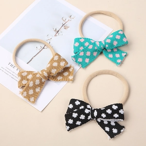 Three knitted floral polka dot bow headbands for infants in mustard, blue, and black