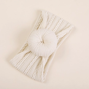 Détail macro du bandeau bébé en maille torsadée blanc cassé avec nœud donut moelleux