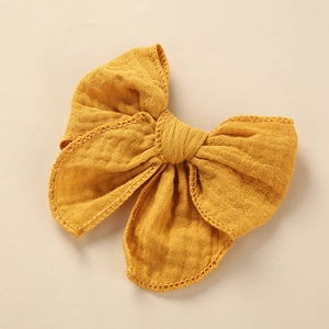 Detail of yellow cotton bow hair clip featuring intricate hollow lace stitching edges