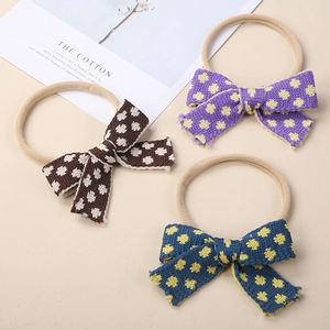 Detailed view of three knitted bow headbands in brown, blue, and purple for infants
