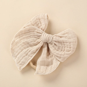 Detail eines Baby Stirnbandes aus weichem Musselin-Stoff mit Schleife in Beige
