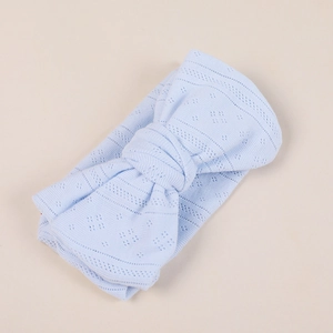 Close-up of light blue knitted baby headband featuring hollow pattern and large bow