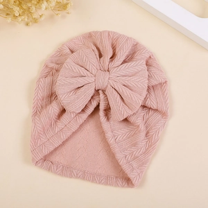 Detail of baby turban with large bow showing pink knit texture and wheat ear pattern