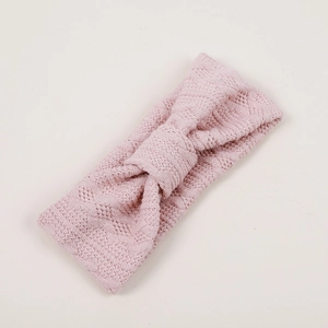 Gros plan détaillé du bandeau tricoté rose pour bébé avec motif de losanges ajourés