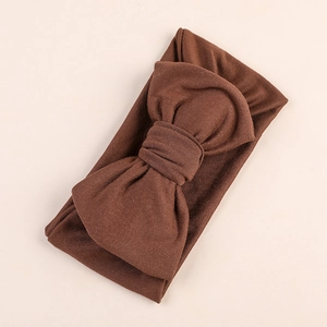 Close-up of a soft milk silk baby headband with a large dark brown bow detail