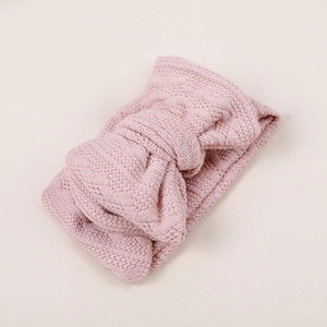 Gros plan d'un bandeau en tricot rose pour bébé avec un nœud et une texture de crochet ajourée