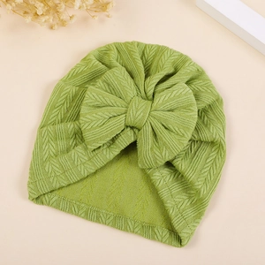 Close-up of baby turban hat with knit texture and large bow in soft light green