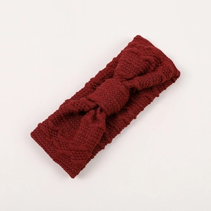 Gros plan du bandeau tricoté rouge foncé pour bébé avec texture torsadée et grand nœud