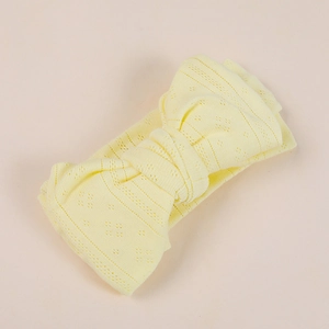 Macro detail of breathable knit texture and large bow on yellow baby headband