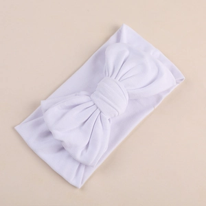 Detailed shot of a soft white milk silk fabric baby headband with a large layered bow