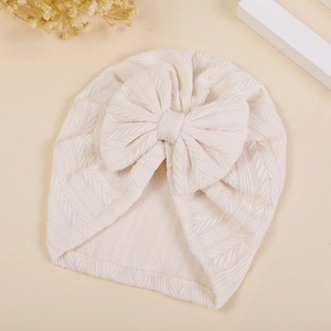 Detailed view of the wheat ear textured bow on the beige baby turban hat