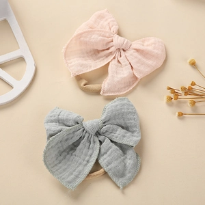 Nahaufnahme von rosa und grauen Baby-Stirnbändern aus Baumwollmull mit weichen Schleifen