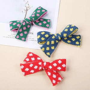 Tre fermagli per capelli a fiocco in maglia con pois su uno sfondo minimalista