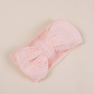 Close-up of pink baby headband with large jacquard knitted bow and soft mesh texture