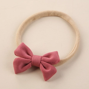 Détail du nœud en tissu rose poudré sur un bandeau élastique en nylon pour bébé