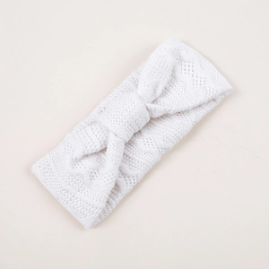 Détail du bandeau tricoté blanc pour bébé avec motifs losanges ajourés et nœud central