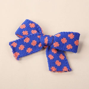 Dettaglio del fermaglio a fiocco in maglia blu reale con pois arancioni per bambine