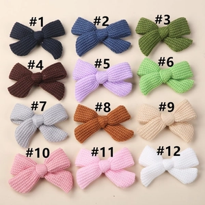 Flat lay of twelve assorted knitted bow hair clips in various vibrant seasonal colors