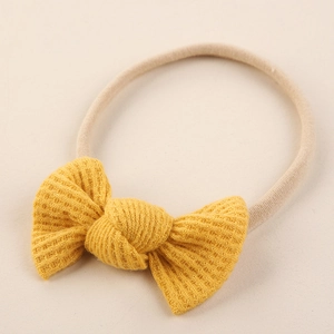 Vue détaillée du nœud en tricot gaufré jaune sur bandeau élastique pour bébé