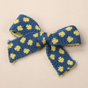 Dettaglio del fiocco in maglia blu con motivi floreali gialli per bambini