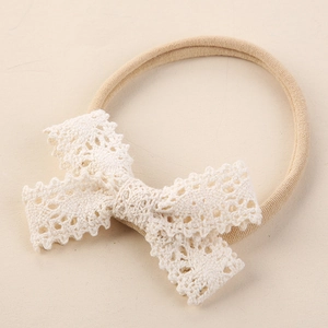 Détail du bandeau bébé avec nœud en dentelle crochetée blanche et ruban nylon beige