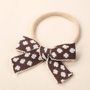 Close-up detail of soft elastic nylon headband with a brown knitted bow for newborn infants