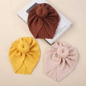 Three-pack of knitted baby donut turbans in brown, yellow, and pink with a soft texture