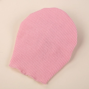 Macro view of pink exfoliator glove showing dense honeycomb knit texture for skin scrubbing