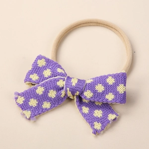 Detail of purple knitted floral bow with yellow dots on soft nylon baby headband