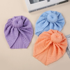 Flat lay of striped knit baby donut hats in purple, light blue, and pink colors