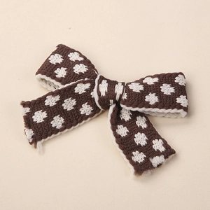 Dettaglio del fiocco in maglia marrone scuro con pois bianchi per accessori capelli bimbi