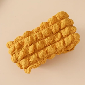 Vue détaillée du tissu popcorn jaune vif et de la texture élastique du bandeau pour bébé