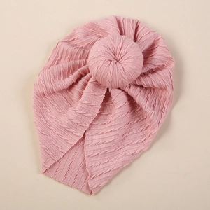 Detailed knit texture of pink baby turban hat with decorative donut knot detail