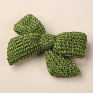 Detailed macro view of grass green knitted bow hair clip featuring thick wool texture