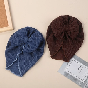 Flat lay of soft knit baby turbans in navy and brown featuring large bow details